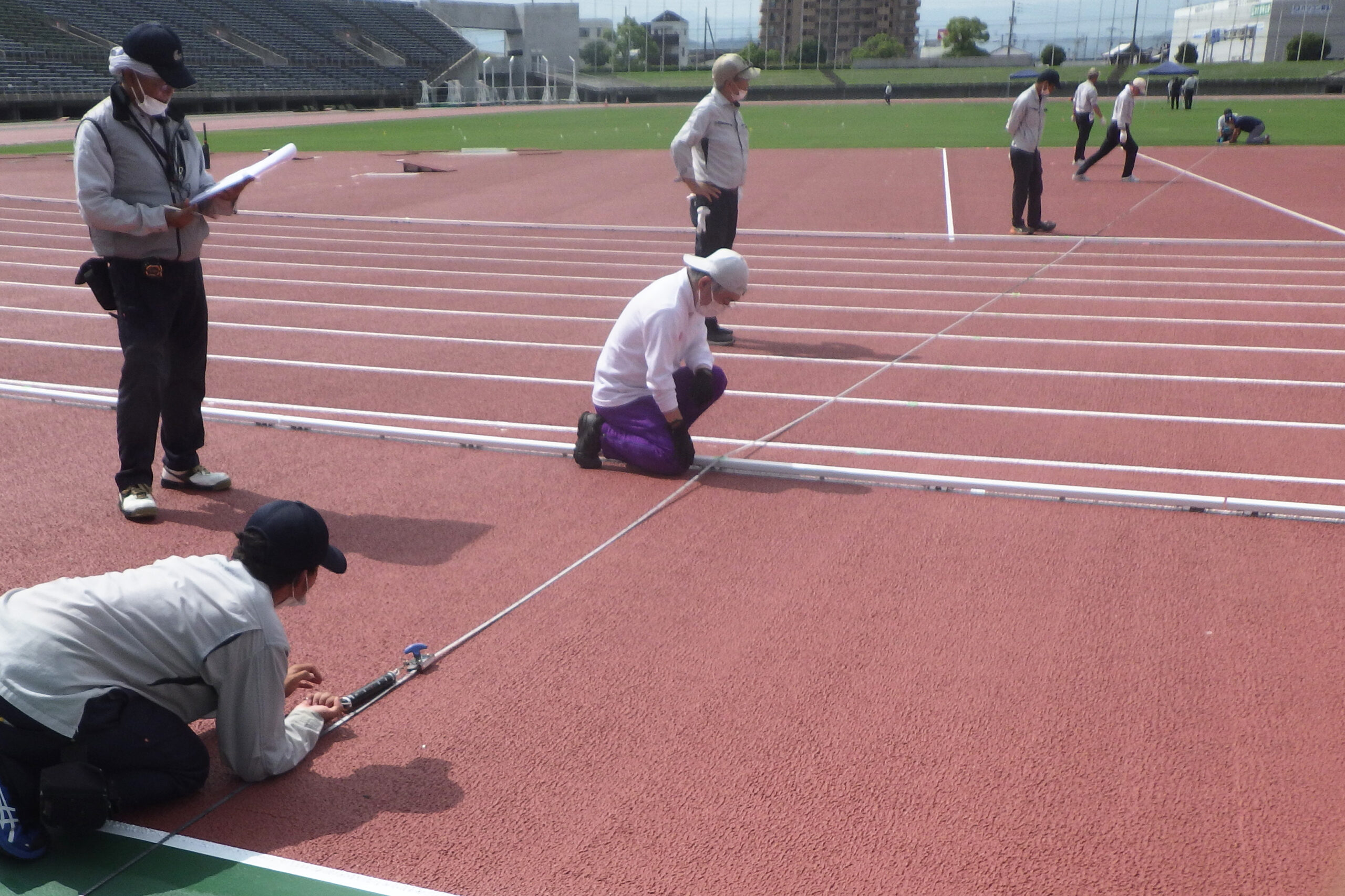 陸上トラックの公認検定において、日本陸連の検定尺を用いてレーンの距離を測定している様子